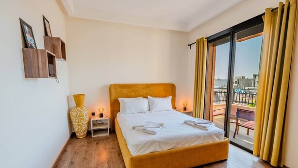 A hotel room with a bed, a nightstand, a vase, and a view of the outside. - Flextay - VILLA Lounge - 4Ch - Pool - Billiards (Marrakesh)