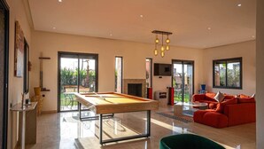 A modern living room with a pool table, a red sofa, and a dining area. - Flextay - VILLA Lounge - 4Ch - Pool - Billiards (Marrakesh)