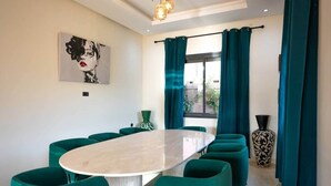 A modern meeting room with a round table, green chairs, a large vase, and a painting on the wall. - Flextay - VILLA Lounge - 4Ch - Pool - Billiards (Marrakesh)