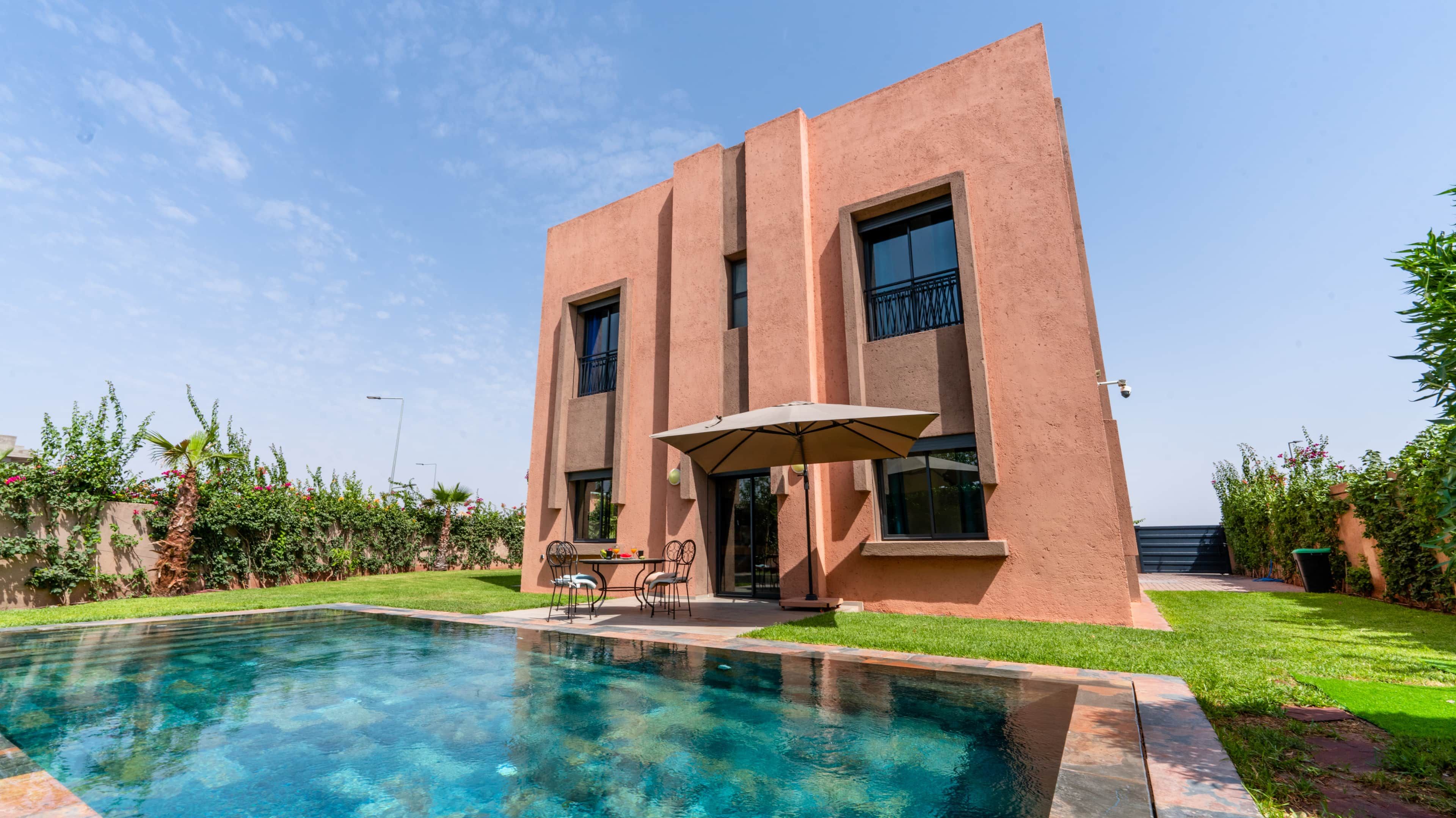 A modern building with a swimming pool, outdoor seating, and a well-maintained garden.