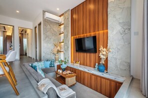 Ein modernes Wohnzimmer mit einer Couch, einem Couchtisch, einem an einer Holzwand montierten Fernseher und einer Marmor-Spritzschutzwand.