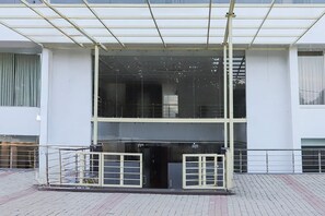 Un edificio con ingresso coperto, un'area recintata e un vialetto lastricato.
