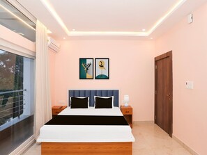 A modern bedroom with a large bed, two bedside tables, a nightstand, a window with curtains, and two wall-mounted artworks.