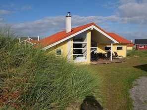 A yellow building with a red roof, a chimney, and a patio with outdoor furniture. - 4 Star Holiday Home in Grossenbrode (Grossenbrode)