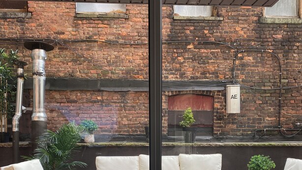 Un patio con muro de ladrillo, chimenea y una zona de estar.