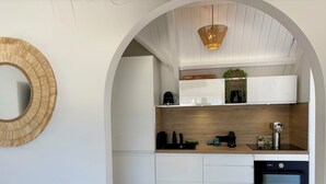 Una cucina moderna con mobili bianchi, forno nero e zoccolo in legno.