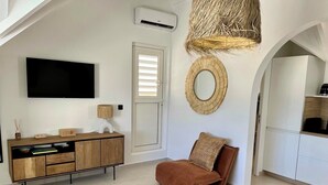 A modern living room with a TV, wooden cabinet, brown sofa, and a large mirror. - Waterfront studio in Saint-Martin (baie nettlé)