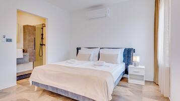 Una habitación de hotel moderna con cama, mesita de noche y unidad de aire acondicionado.