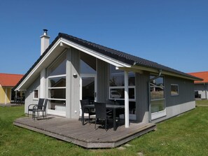 Ein modernes Haus mit einer großen Terrasse, einem Schornstein und einer Garage.