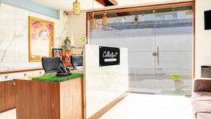 A reception desk with a sign, a wooden counter, a framed picture, and a potted plant. - Classic With Balcony Ubale Nagar (Pune)