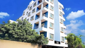 A multi-story building with balconies, a sign indicating a hotel, and surrounding greenery. - Classic With Balcony Ubale Nagar (Pune)