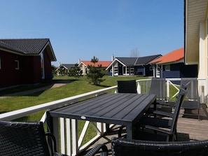 Eine Terrasse mit Gartenmöbeln, freier Sicht auf die umliegenden Gebäude und einem gepflegten Rasen.