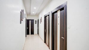 A corridor with doors, framed pictures, and a tiled floor. - Deluxe With Twin Bed Hotel Sky Inn (Lucknow)