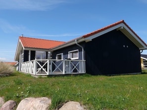 A two-story house with a red-tiled roof, a balcony with white railings, and a dark blue exterior. - 4 Star Holiday Home in Grossenbrode (Grossenbrode)