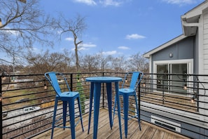 A deck with two blue chairs and a small table, overlooking a residential area with trees and a house. - Nashville Group Retreat Sleeps 10 Near Downtown (Nashville)