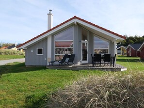 A modern single-story building with a covered patio, a chimney, and a number '132' sign. - 4 Star Holiday Home in Grossenbrode (Grossenbrode)