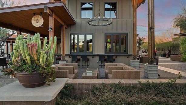 Un bâtiment à la façade en bois, doté d’une terrasse et d’une grande plante en pot.