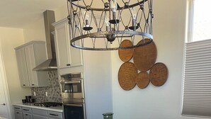 Un coin repas avec une table ronde, des chaises, un grand vase et une cuisine en arrière-plan.