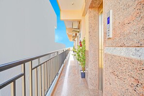 A corridor with a metal railing, a potted plant, and a wall-mounted elevator control panel. - Super Hotel O Yeshwanthpur (Bengaluru)