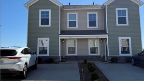 A two-story house with a front porch, two garages, and a driveway.