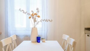Et hvidt bord med en vase med blomster, et blåt glas og en lille plante.