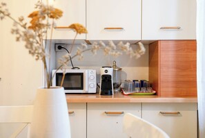A kitchen with white cabinets, a microwave, a coffee maker, and a vase with dried flowers. - Venice Mestre Station Entire Apartment Oscar House (Venezia)