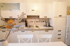 Una cocina moderna con armarios blancos, una isla central y un jarrón con flores secas.