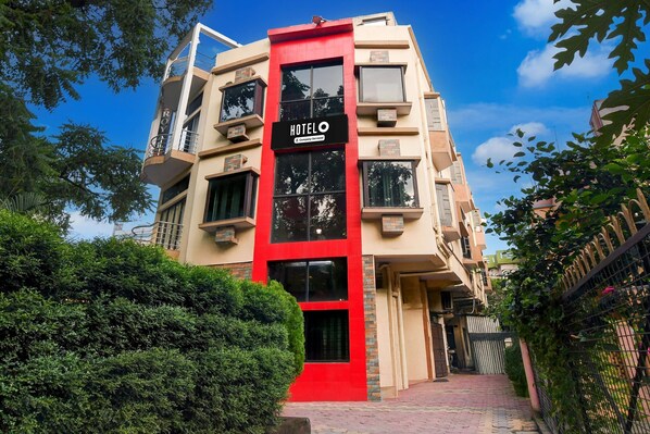 Un edificio de hotel con una franja vertical roja, balcones y cielo despejado.