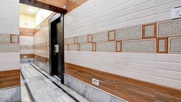Un pasillo con paredes de azulejos, suelo de mármol y una puerta que da a otra habitación.