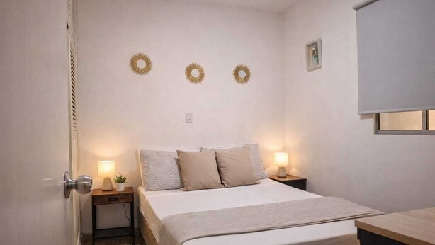 Un dormitorio con una cama, dos mesitas de noche, lámparas de pared y tres adornos murales.