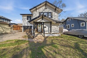 A two-story house with a front porch, a garage, and a covered vehicle.