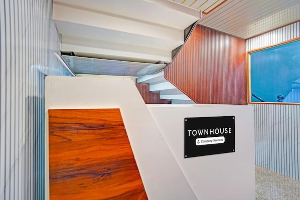 Un interior moderno con una escalera, un cartel que dice 'TOWNHOUSE Company Serviced' y una pared azul.