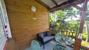Ein Holzbalkon mit einer Couch, zwei Stühlen, einem Tisch und einem 'Bienvenue'-Schild.