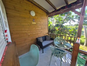 A wooden balcony with a sofa, two chairs, a table, and a 'Bienvenue' sign. - A bird's paradise Cozy country bungalow (Saint-François)
