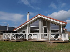 A single-story building with a red roof, white exterior, and a balcony with white railings. - 4 Star Holiday Home in Grossenbrode (Grossenbrode)