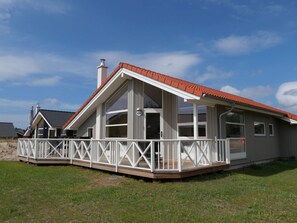 A two-story house with a red-tiled roof, a covered porch with white railings, and a number '123' on the front door. - 4 Star Holiday Home in Grossenbrode (Grossenbrode)