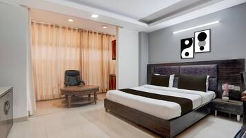 Una habitación de hotel moderna con una cama grande, un escritorio, una silla y una puerta corrediza cubierta por una cortina.