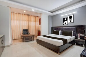 Una habitación de hotel moderna con una cama grande, un escritorio, una silla y una puerta corrediza cubierta por una cortina.