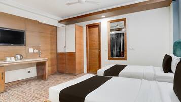 Habitación de hotel con dos camas, un escritorio, un televisor y un armario.
