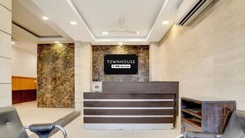 A reception area with a marble wall, a sign indicating it's serviced by OYO, and two black leather chairs.