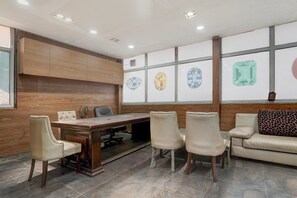 Un salón de conferencias con pared de paneles de madera, una mesa grande y seis sillas.