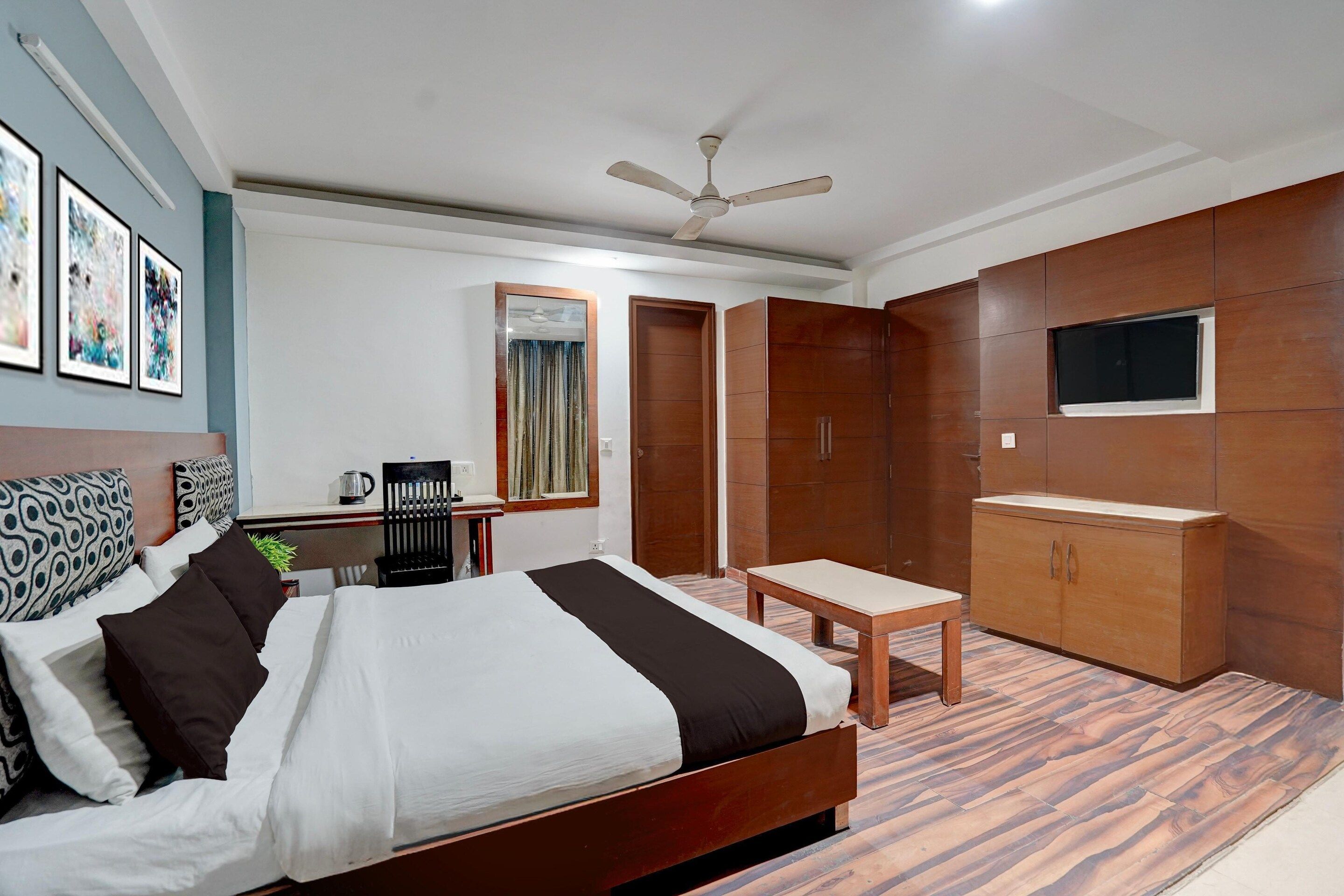 A hotel room with a bed, a desk, a chair, a TV, and a wardrobe.