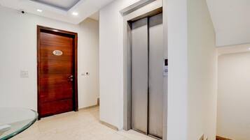 A hallway with a wooden door marked '311' and a modern elevator.