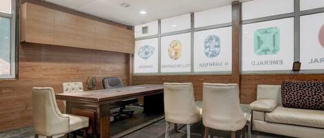 A conference room with a wooden panel wall, a long table, and four chairs.