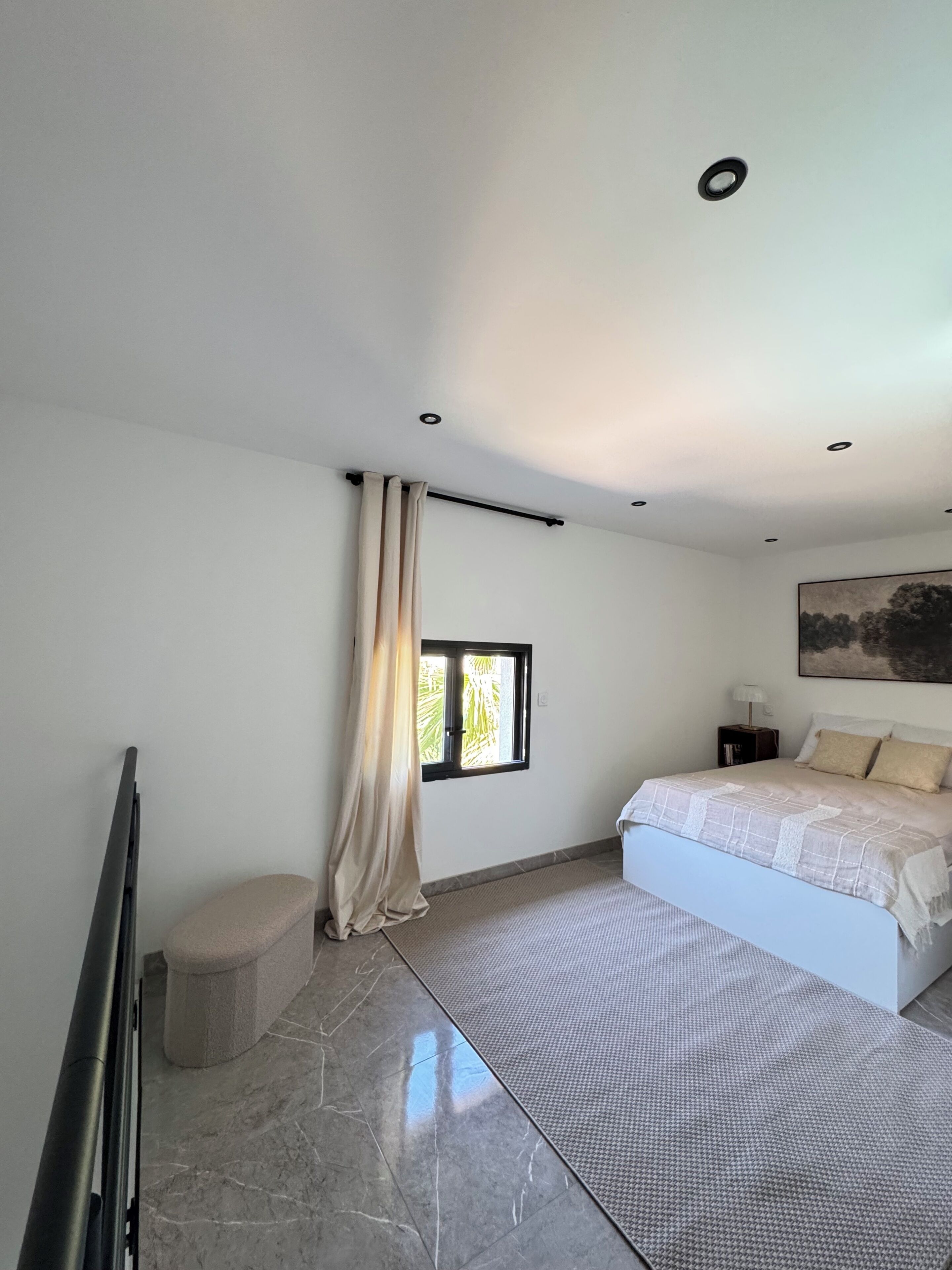 Una camera da letto con un letto, una finestra, un comodino e un quadro appeso al muro.