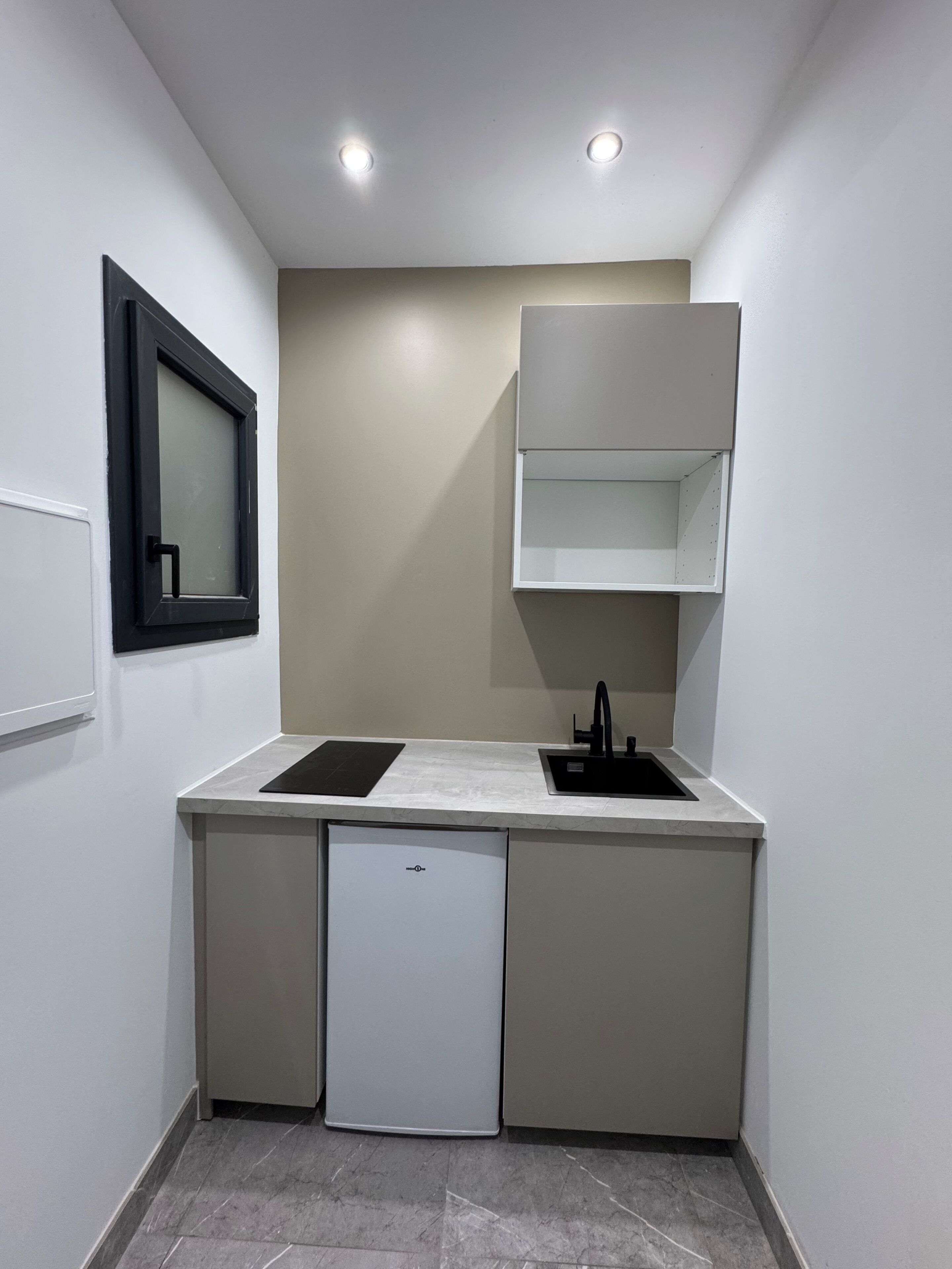 A compact kitchen with a built-in dishwasher, a sink, and a small cabinet.