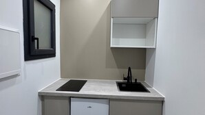 Eine kompakte Küche mit eingebautem Geschirrspüler, Spüle und kleiner Schrank.