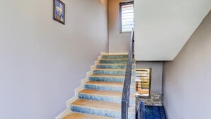 Una escalera con barandilla, un cuadro en la pared y una ventana en la parte superior.