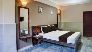 Une chambre d’hôtel équipée d’un lit, de tables de chevet, d’un miroir et de lampes fixées au mur.