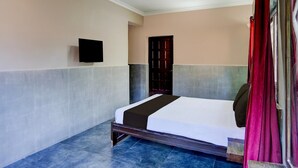 Una habitación con una cama, un televisor montado en la pared y una puerta.